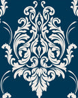 Classic damask wallpaper with crisp ivory ornamental scrollwork on a deep teal blue background.