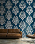 Classic damask wallpaper with crisp ivory ornamental scrollwork on a deep teal blue background.