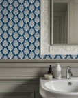 Classic damask wallpaper with crisp ivory ornamental scrollwork on a deep teal blue background.