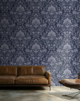 Vintage damask wallpaper with distressed ivory scrollwork and ornate floral motifs on a deep navy blue background.