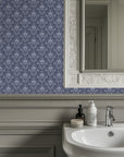 Vintage damask wallpaper with distressed ivory scrollwork and ornate floral motifs on a deep navy blue background.