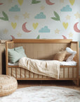 A soft white wallpaper, suitable for a nursery, featuring a scattered pattern of whimsical pastel elements: stars, moons, clouds, hearts, and foliage