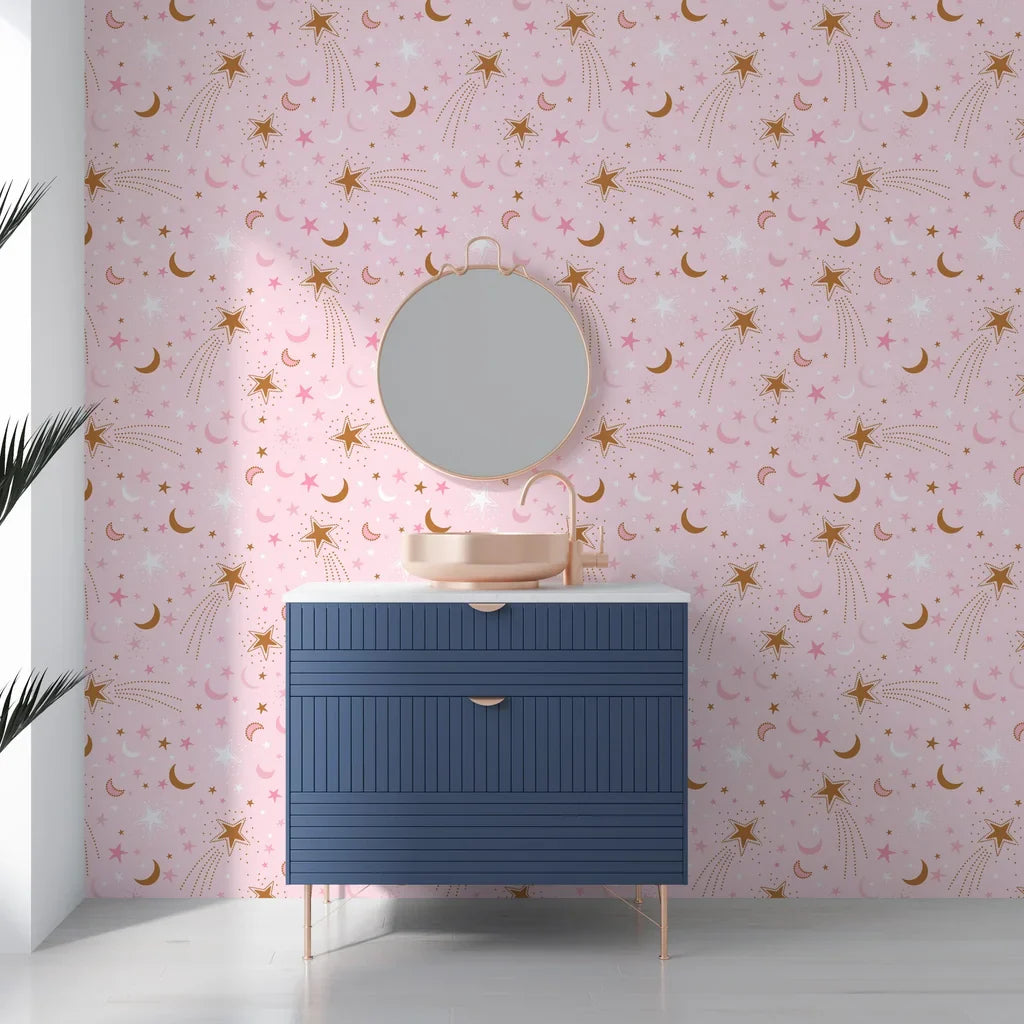 A dreamy night sky scene with golden lunar shapes and sparkling stars on rose-colored removable wallpaper - Celestial Blush
