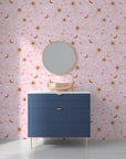 A dreamy night sky scene with golden lunar shapes and sparkling stars on rose-colored removable wallpaper - Celestial Blush