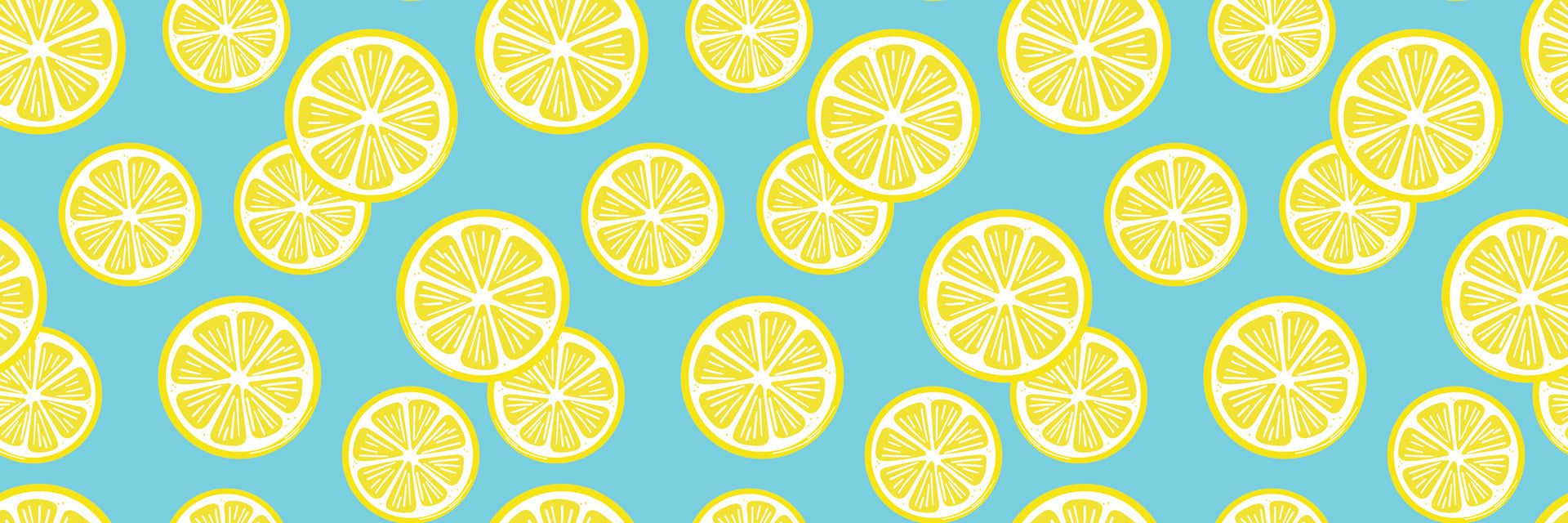 Greenery and vivid yellow citrus fruits are arranged flowing diagonally across the white space