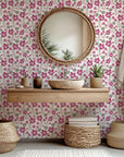 A green and magenta botanical design on wall covering, featuring a distinctive textured brush finish - Crimson Grove