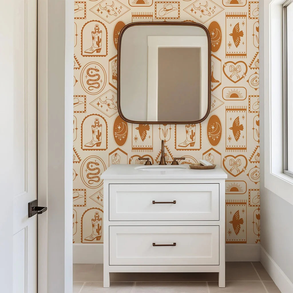This iconographic Western wallpaper utilizes a warm palette of clay and earth tones to depict desert landscapes, snakes, moons, boots, and horseshoes.