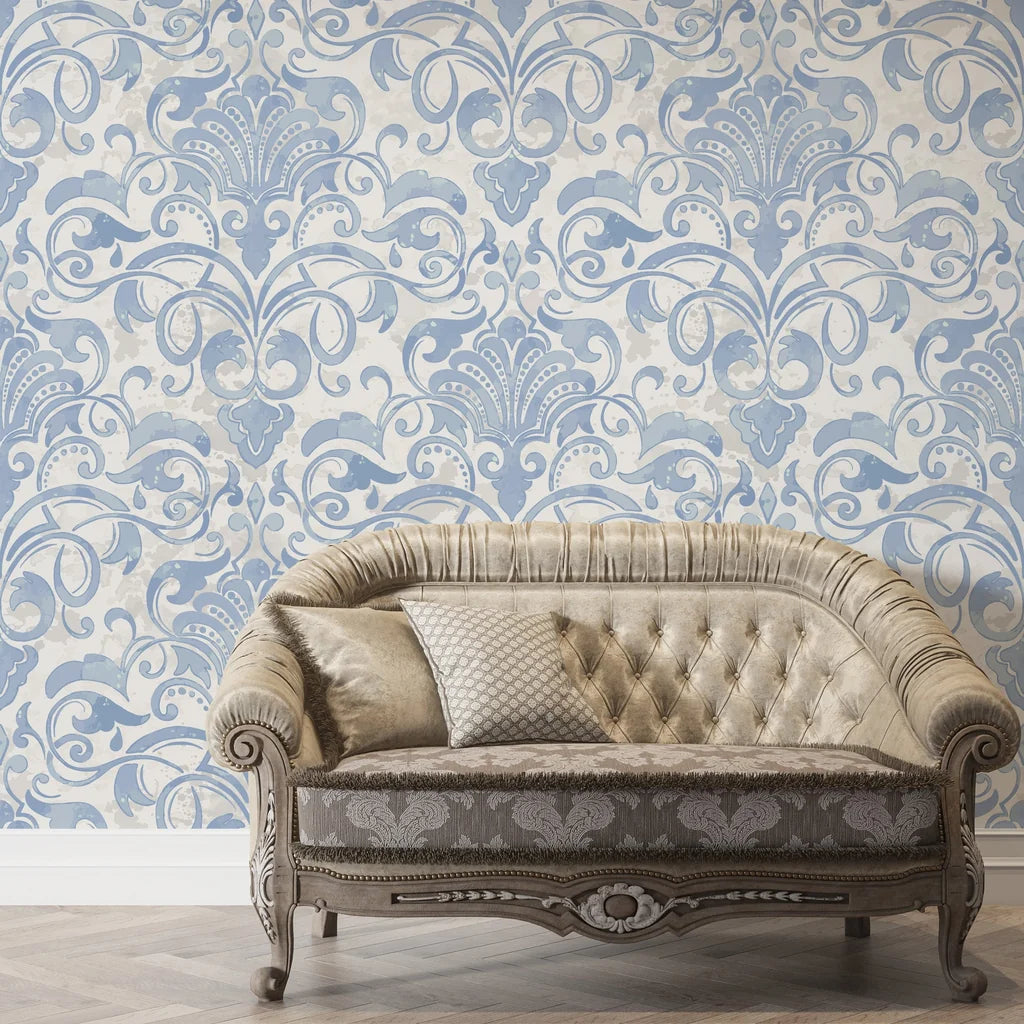 Dusky Garden Waltz removable wallpaper with blue damask scrolls on cream, styled behind tufted vintage sofa