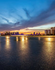 Dramatic sunset cityscape with blue and golden skies reflected on water, Embers On The Horizon wallpaper mural