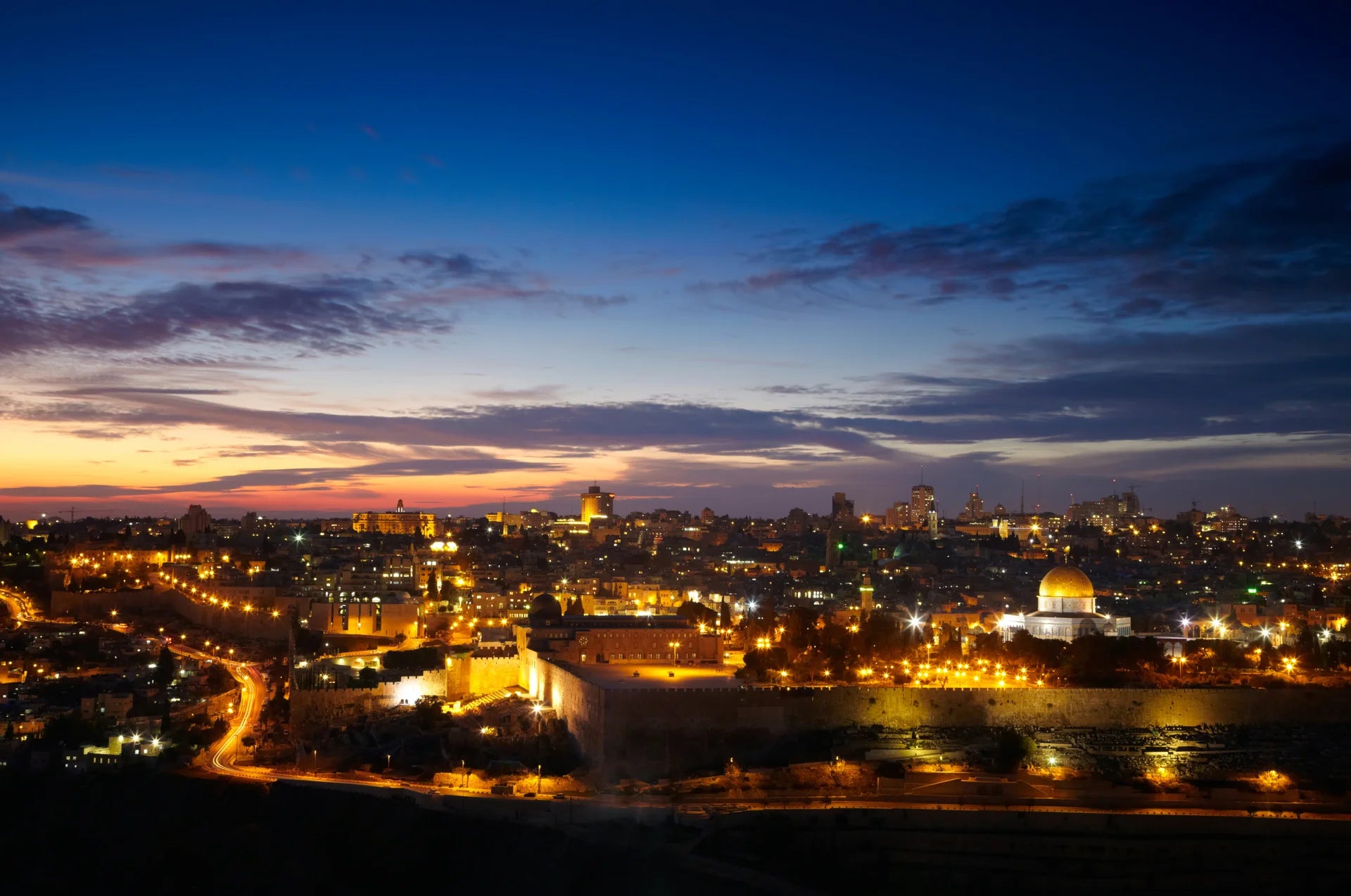 Dramatic First Light wallpaper featuring Jerusalem skyline at dusk with golden city lights and blue sunset sky