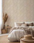 Neutral beige wallpaper with vertical, organic wave lines that resemble soft woodgrain or flowing natural fibers in a repeating pattern.