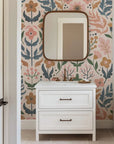Softly colored, traditional wall treatment displaying a stylized floral and berry motif. The design uses muted pink, dusty blue, sage, and ochre hues, sitting upon a light blush background.