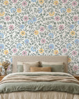 Garden Reverie floral wallpaper with pink, blue, and yellow blooms on sage green vines in modern bedroom