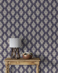 Navy and cream Gentlebotan damask wallpaper on living room wall with rustic wood table and chevron lamp