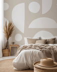 Abstract geometric wallpaper with white organic shapes and half circles scattered across a warm beige background.
