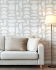 Abstract geometric wallpaper with white organic shapes and half circles scattered across a warm beige background.