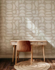 Abstract geometric wallpaper with white organic shapes and half circles scattered across a warm beige background.