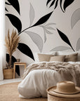 Abstract botanical wallpaper with flowing black leaves and fine line drawn foliage on a warm ivory background.