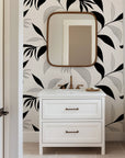 Abstract botanical wallpaper with flowing black leaves and fine line drawn foliage on a warm ivory background.