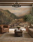 Hilltop Manor landscape mural wallpaper featuring mountains, stream, and trees in earth tones on living room wall