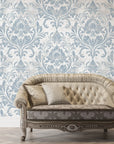 Blue and cream damask Honeyed Petal wallpaper on elegant living room wall with tufted sofa