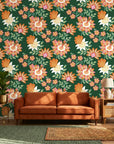 Jungle Solstice floral wallpaper with orange and pink blooms on forest green behind tan leather sofa