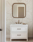 Neutral beige wallpaper with repeating hand drawn geometric blocks made of white linear brush strokes.