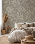 Hand drawn botanical wallpaper pattern with delicate leafy branches, crescent moons, and small stars on a warm taupe background, creating a soft celestial nature inspired design.