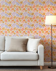 Playful abstract botanical wallpaper with hand painted leaf and floral shapes in peach, lavender, ochre, and soft coral on a warm cream background.