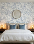 Blue and cream Midnight Bloom Drift wallpaper with distressed floral pattern in serene bedroom setting