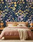 Navy blue Midnight Bouquet wallpaper with yellow daisies and pink florals behind modern bedroom with blush bedding
