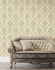 Gold damask Misty Fern Romance wallpaper on cream background with vintage tufted sofa in elegant living room