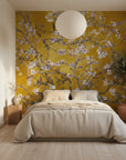 Golden mustard Monet's Garden wallpaper with cherry blossoms on minimalist bedroom accent wall
