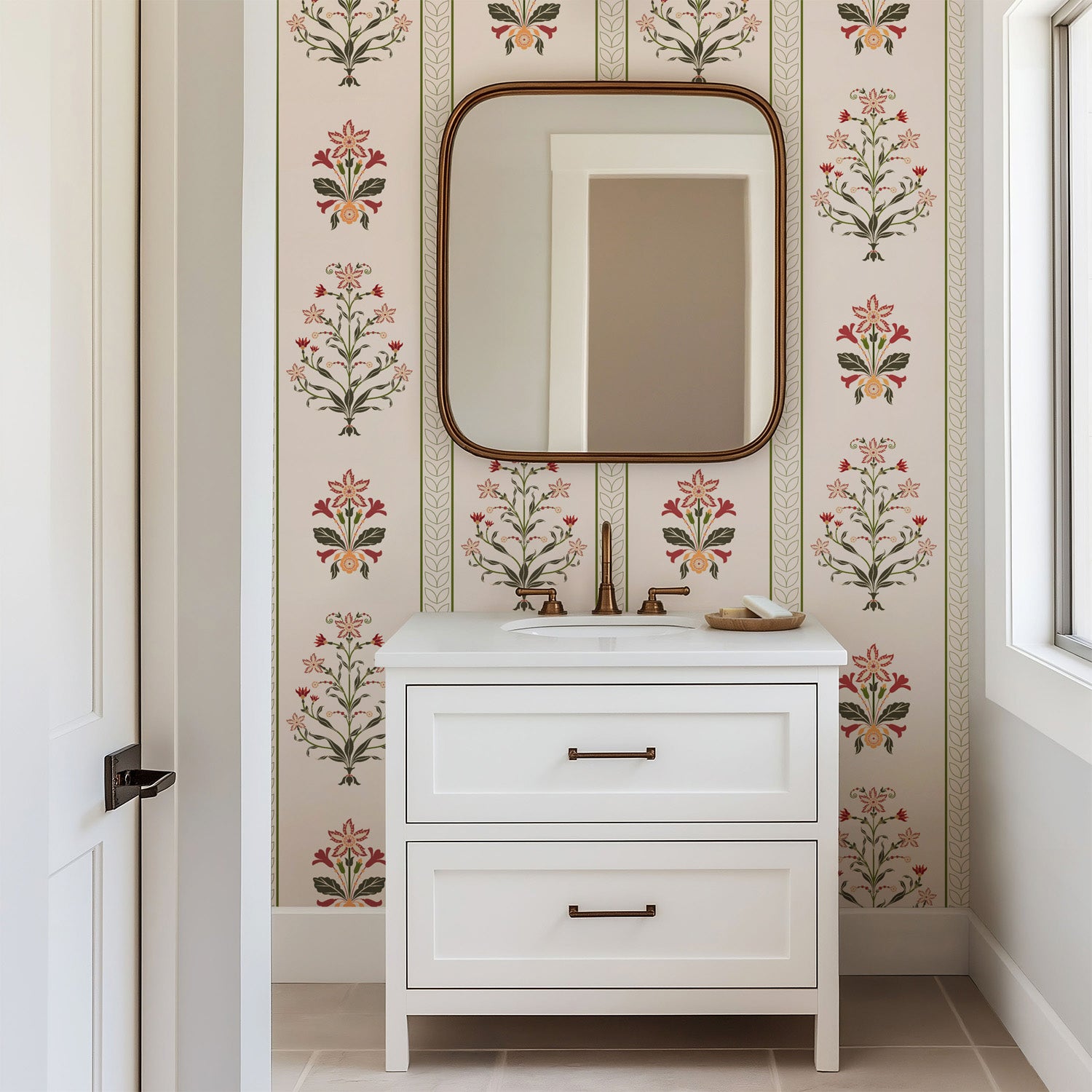 Vertical floral stripe wallpaper with symmetrical folk inspired flowers in red, olive green, and soft peach on a warm cream background.