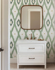 Soft sage green ikat wallpaper with hand painted diamond shapes and subtle gold accents on a white background.