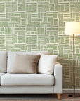Olive green abstract wallpaper with hand drawn brush stroke blocks arranged in a loose geometric grid on a warm cream background.