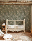 Removable nursery wallpaper featuring a repeat design of deer and coniferous trees in a soft earth-toned green - Silent Woods