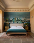 Teal and gold New York skyline Teal Nocturne wallpaper behind bedroom headboard at dusk