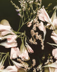 Moody The Still Hour wallpaper featuring blush pink flowers and lavender stems on dramatic black background