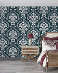 Dark teal and cream Veiled Botany damask wallpaper on bedroom accent wall with vintage furnishings