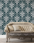 Dark teal and cream Veiled Botany damask wallpaper behind vintage tufted sofa in elegant living room