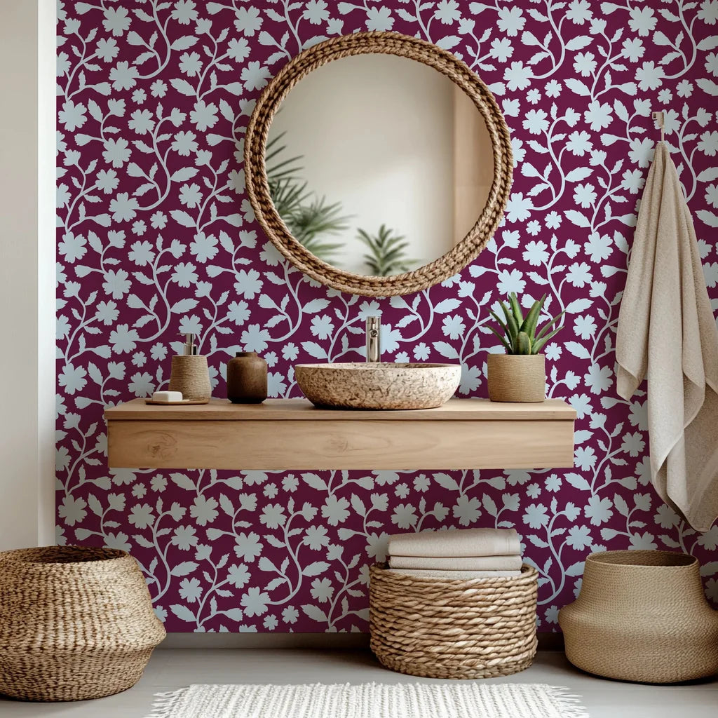 A removable, self-adhesive wallpaper in deep red (burgundy) adorned with a pale blue floral silhouette pattern, named Velvet Bloom.