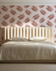 Acacia Scatter Oxblood dainty leaf wallpaper behind a channel-tufted bed in a calm primary bedroom