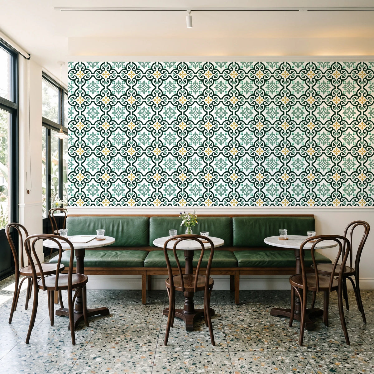 Andalusian Court Emerald encaustic tile wallpaper above a green leather banquette in a sunlit neighborhood cafe