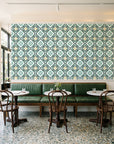 Andalusian Court Emerald encaustic tile wallpaper above a green leather banquette in a sunlit neighborhood cafe