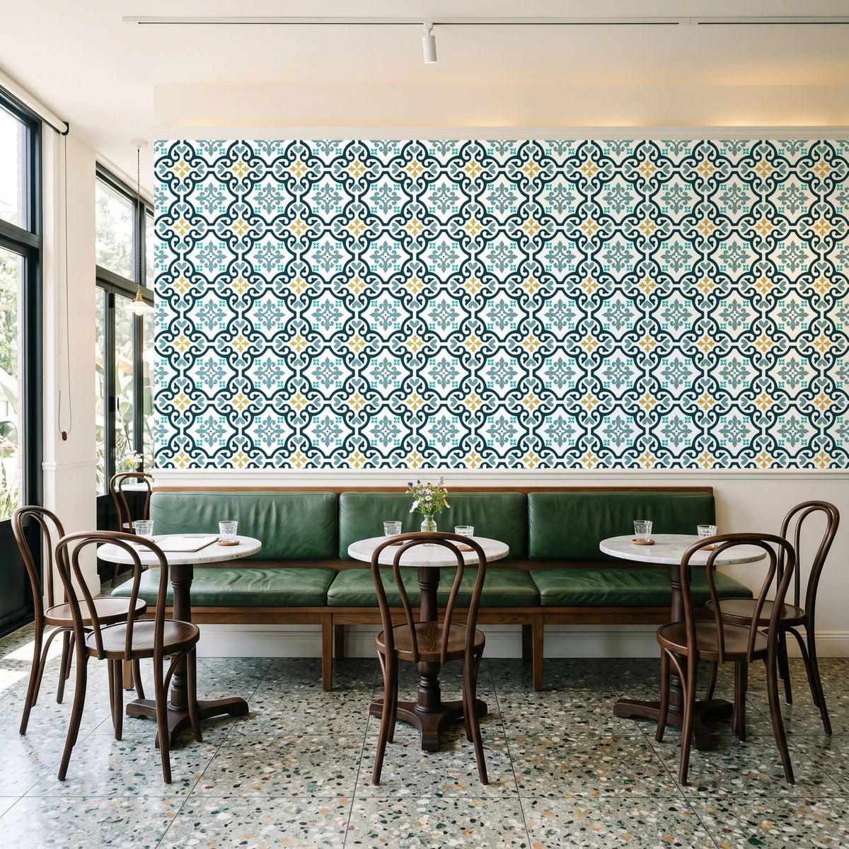 Andalusian Court Peacock encaustic tile wallpaper above a green leather banquette in a sunlit neighborhood cafe