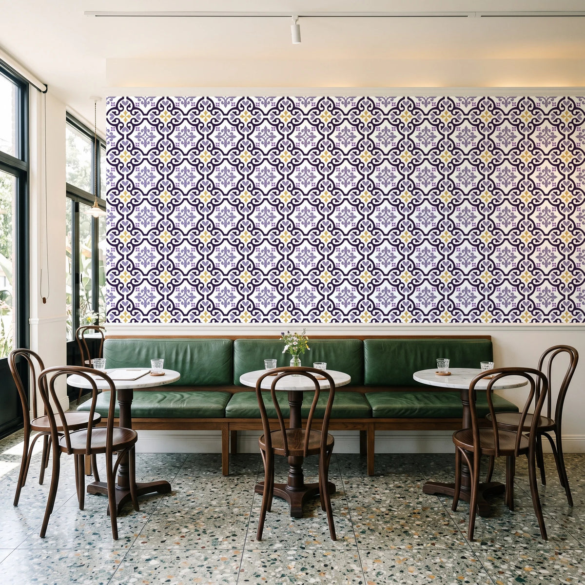 Andalusian Court Plum encaustic tile wallpaper above a green leather banquette in a sunlit neighborhood cafe