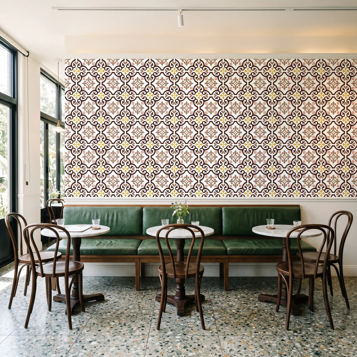 Andalusian Court Terracotta encaustic tile wallpaper above a green leather banquette in a sunlit neighborhood cafe