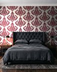 Antique Fern Mist Garnet distressed damask wallpaper behind a tufted headboard in a dark, moody bedroom
