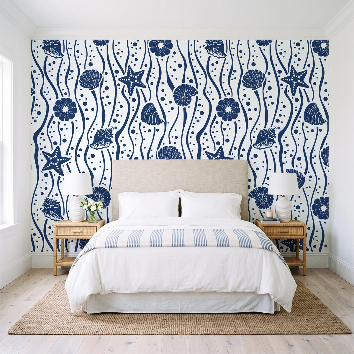 Apricot Tides Navy coastal seashell wallpaper behind a queen bed in a bright coastal bedroom